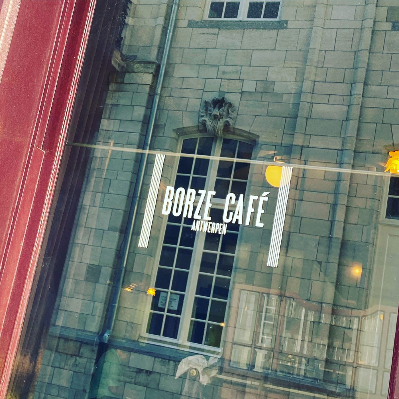 Gouden logo op het raam met de oude Beurs in de weerspiegeling, Borze Café Antwerpen